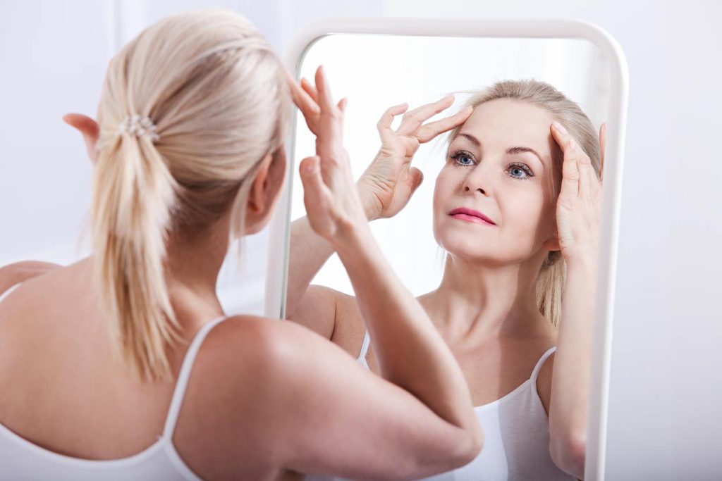Middle aged woman admiring her smooth firm forehead.  Wolin Plastic Surgery Center.